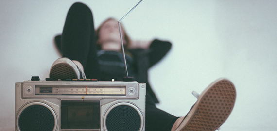 Symbolbild Entspannung: Frau liegt am Boden und legt einen Fuß auf einen Kassettenrekorder, Photo by Eric Nopanen on Unsplash